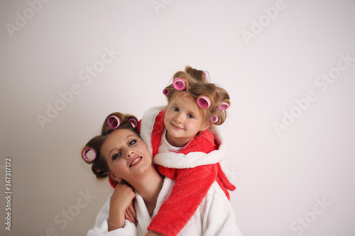 Mom and baby girl are in bathrobes and curlers on her head.