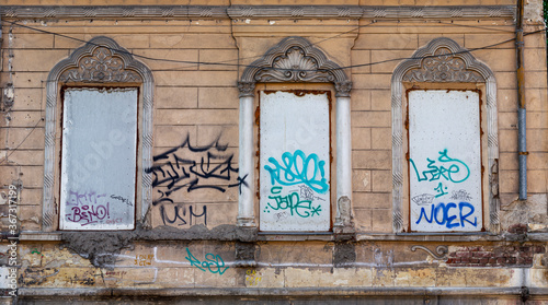 Triptych of (three) covered up old windows with architectural motifs and graffiti in dereliction state
