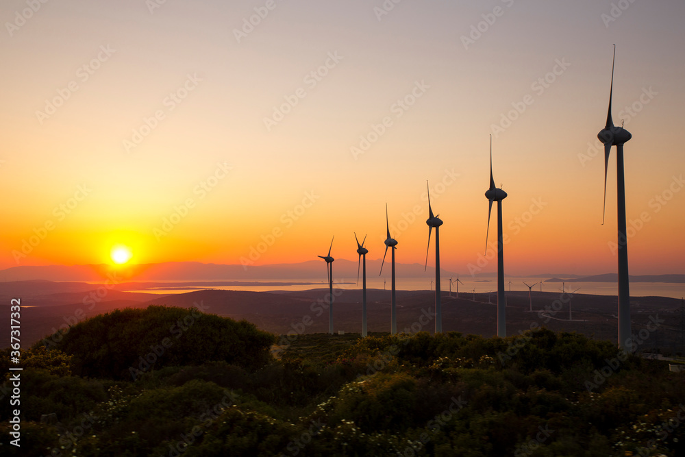 Obraz premium Scenic view of windmill farm at sunset time