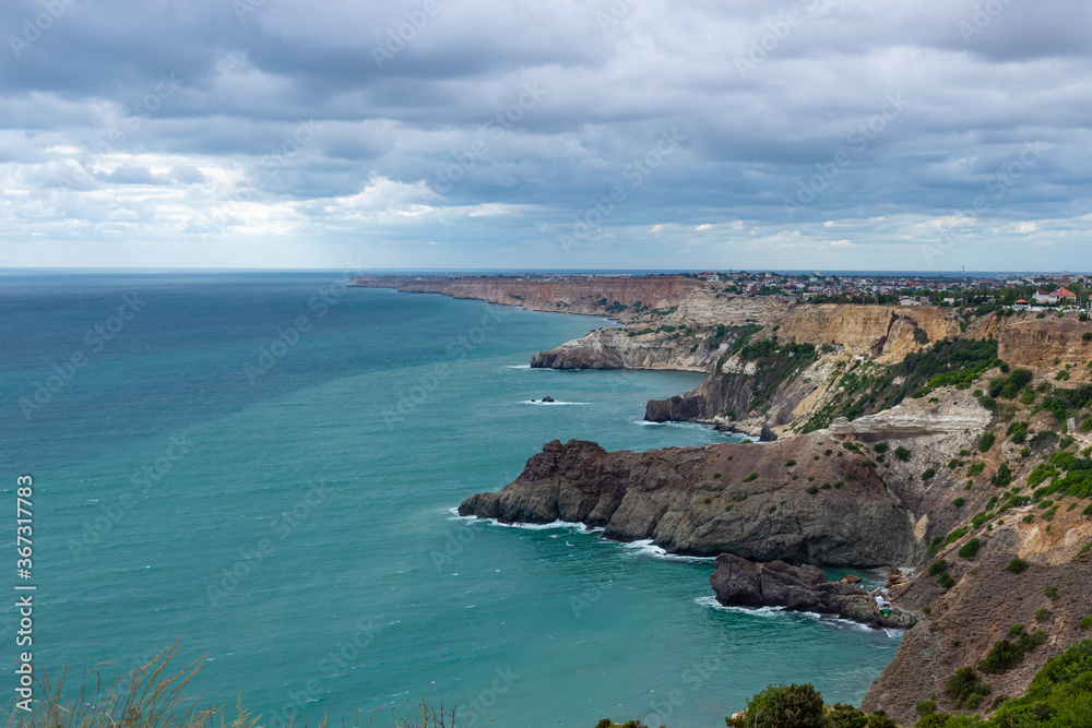 Fototapeta premium beautiful seascape of Cape Fiolent, Crimea. Calm azure sea and rocky coast. Sky with blue clouds. City by the sea.