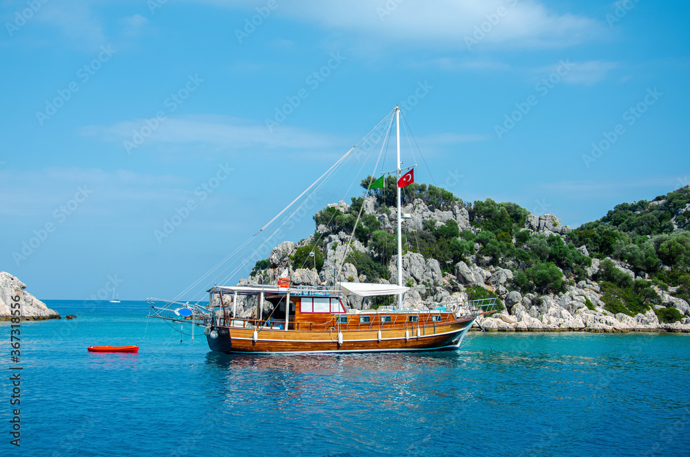 Fototapeta premium Tourist ship on the background of a beautiful summer mountain landscape on the Mediterranean sea. Excursion to Turkey. Sea tour of the historical monument of architecture. People on vacation
