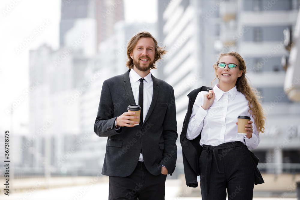 Confident business partners walk around the city with coffee during lunch break. Cheerful and smiling businessmen Confident business partners walk around the city with coffee during lunch break. Cheerful and smiling businessmen