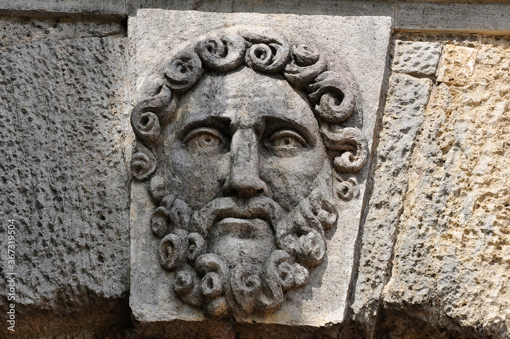 The ancient bas-relief of a male face with a beard.