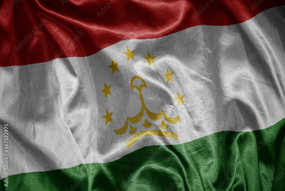 Fototapeta premium colorful shining big national flag of tajikistan on a silky texture