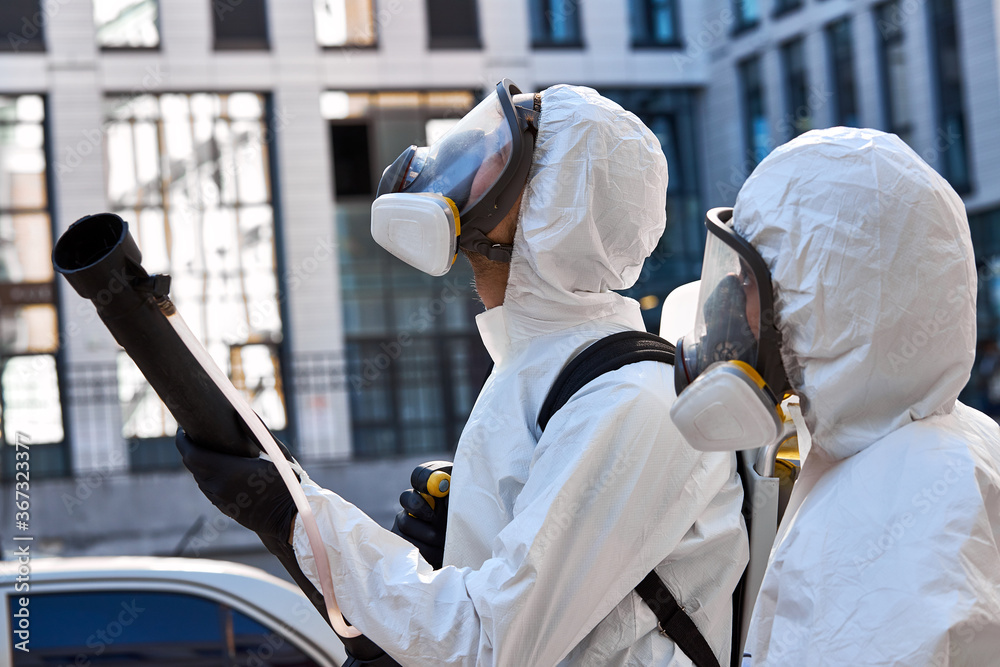 professional cleaning and disinfection of the territory in the city due to the emergence of Covid-19 virus. specialized friendly team in protective suits clean surface with equipment