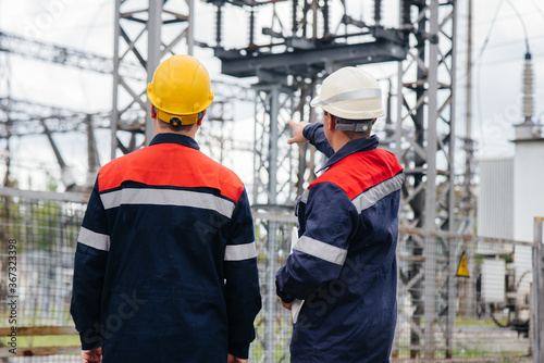 Two specialist electrical substation engineers inspect modern high-voltage equipment. Energy. Industry