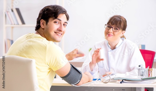 Young doctor checking patients blood pressure