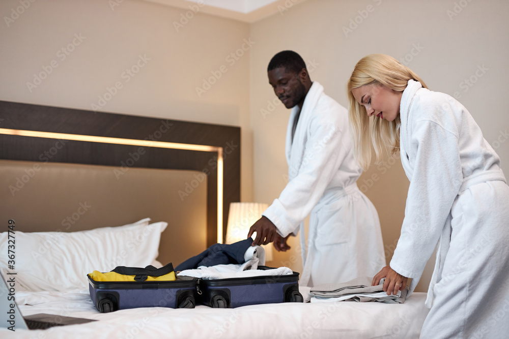 Obraz premium mixed race couple wake up in hotel and preparing to leave the hotel, young married couple lay clothes out