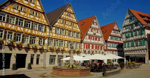 schöne Fachwerkhäuser umrunden den Marktplatz  mit Brunnen in Herrenberg unter blauem Himmel photo