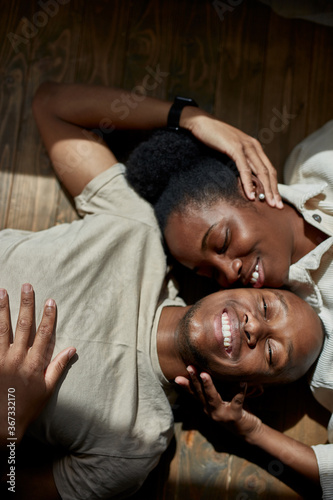 top view on beautiful young black married couple lying on the floor, they are posing at camera, man and woman in love, smile