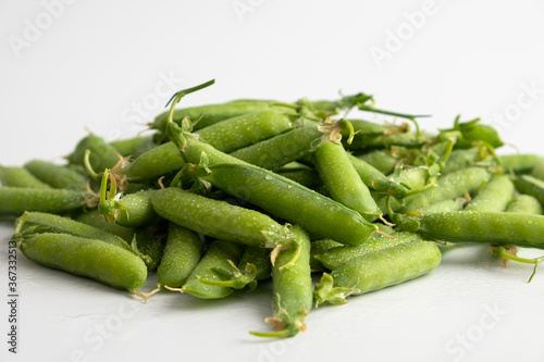 Pods of fresh young green peas close up on a white background