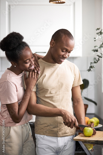 young friendly african couple is cooking together in the kitchen, man and woman happy to prepare meal as one team.
