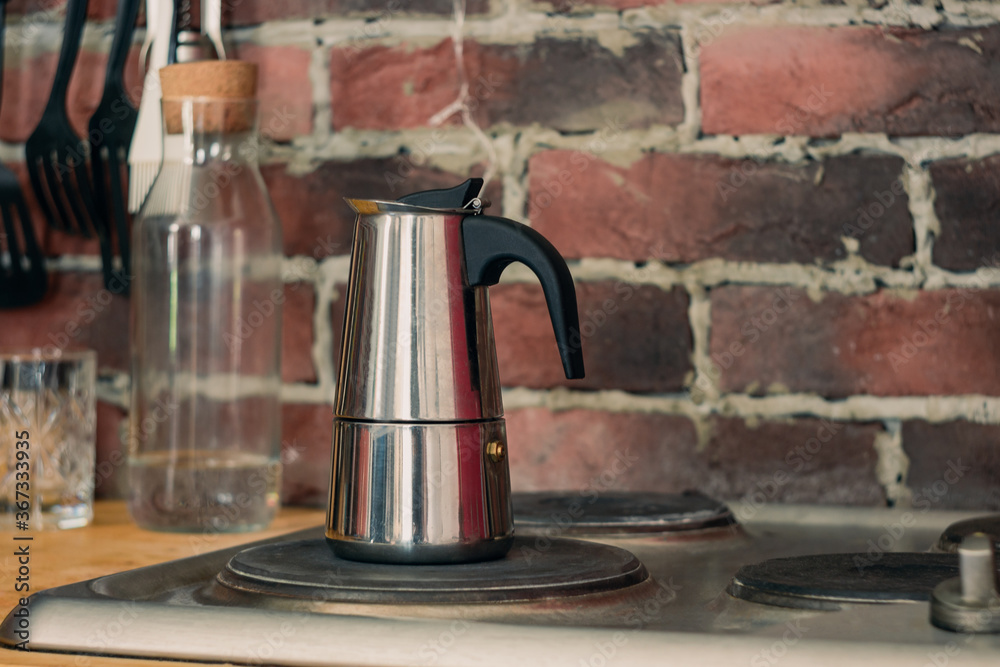 geyser coffee maker is on the stove, coffee is brewed at home, a good morning begins with freshly brewed coffee. Loft design, red brick background geyser coffee maker is on the stove, coffee is brewed at home, a good morning begins with freshly brewed coffee. Loft design, red brick background