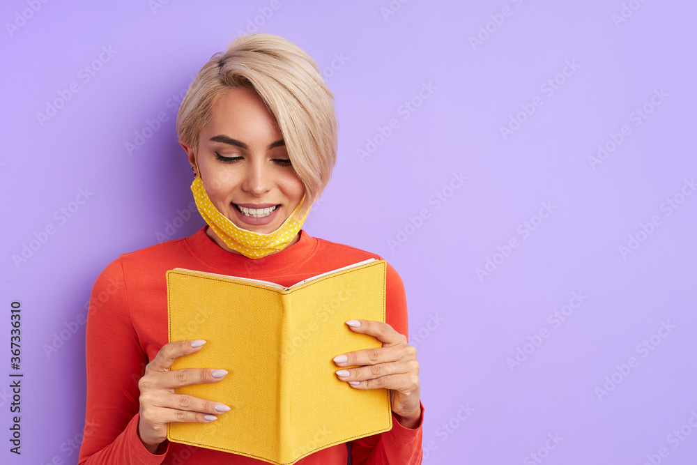 smiling caucasian woman reading a book, in medical protective mask. education, studying concept smiling caucasian woman reading a book, in medical protective mask. education, studying concept