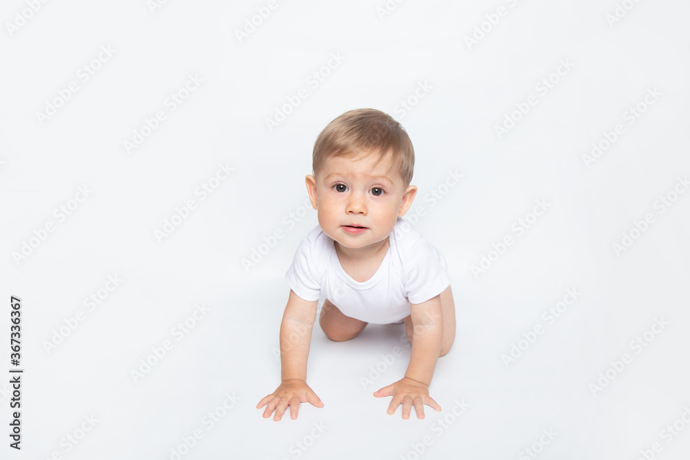 Caucasian hairy baby boy in white t-shirt crawls on all fours on white background Caucasian hairy baby boy in white t-shirt crawls on all fours on white background