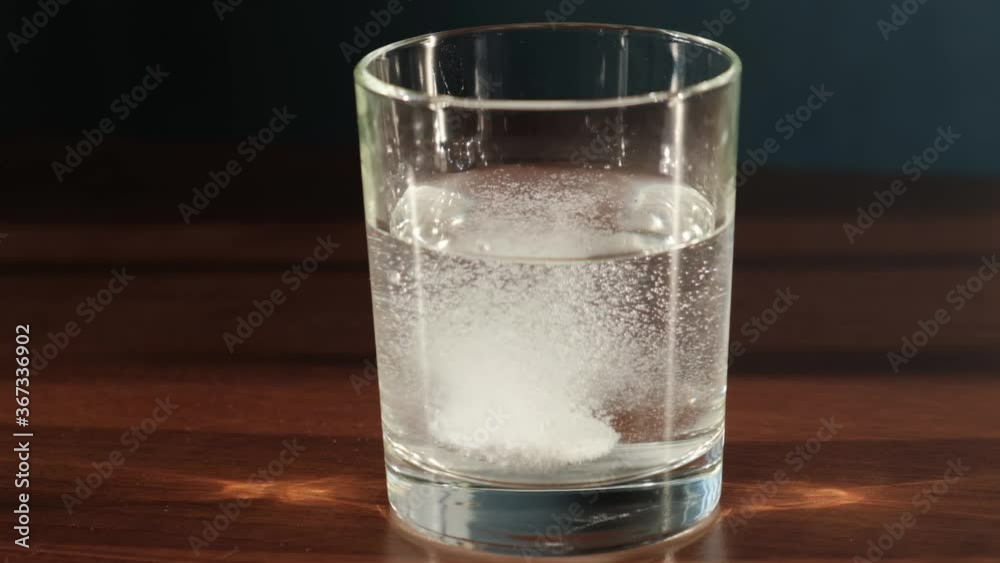 Tablet falling into a glass of water and dissolves with bubbles, slow motion Tablet falling into a glass of water and dissolves with bubbles, slow motion