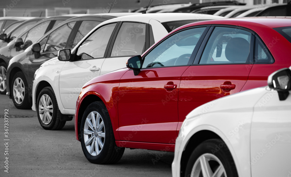 Black and white image of a row of cars. Only the red car has color Black and white image of a row of cars. Only the red car has color