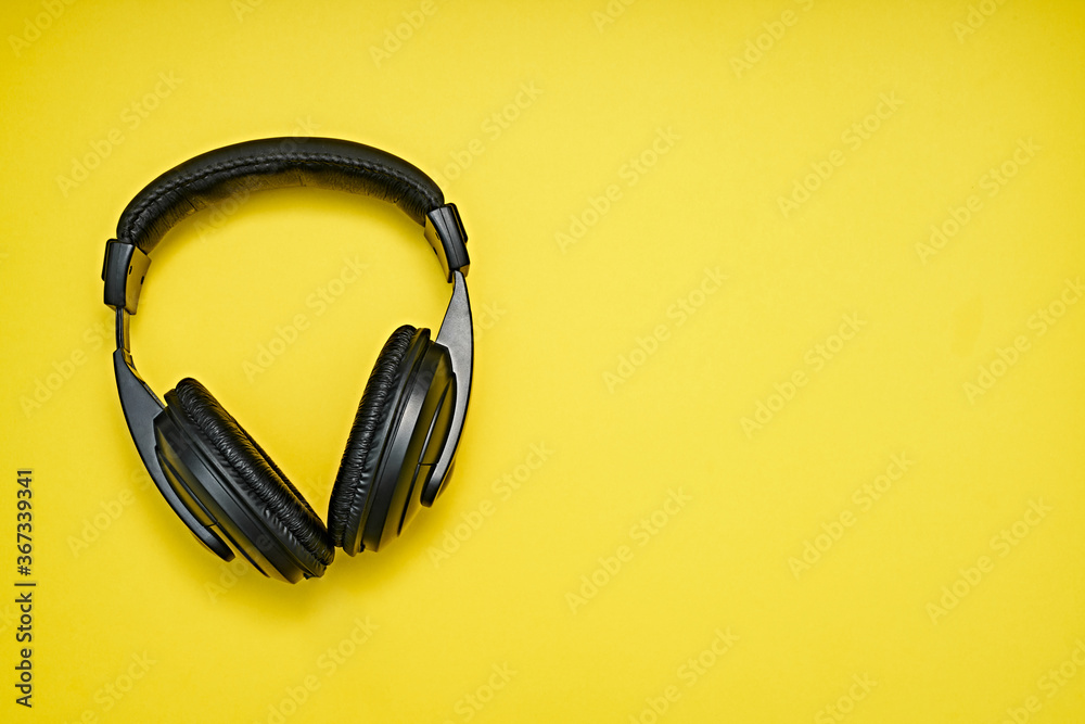 Large, black headphones lie on a colored background. Device for individual listening to music.