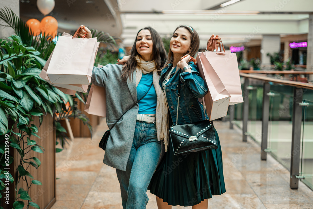 Trade, buyers. Two beautiful girls make purchases in a shopping center, go shopping. The joy of consumption.