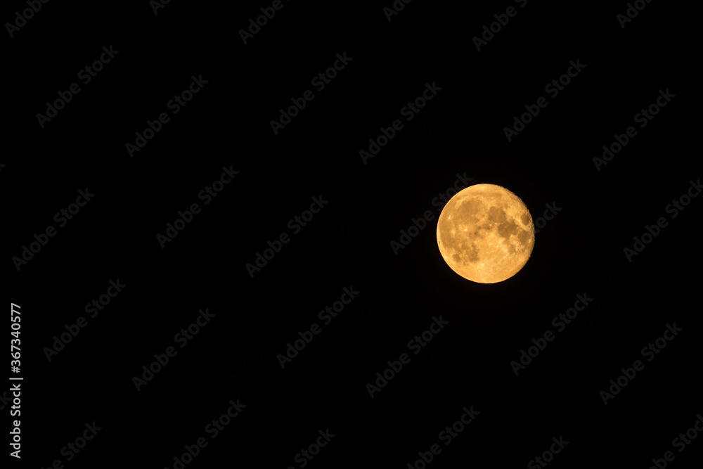 Bright yellow moon in dark almost black sky