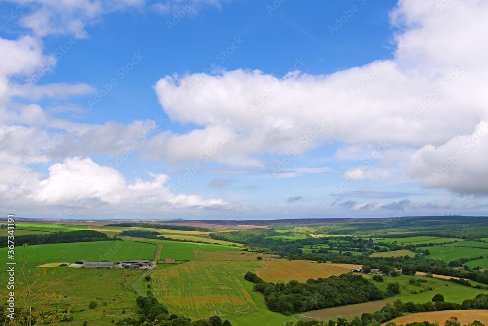 Blue cloudy sky, above farmland and moorland in Harwood Dale, North Yorkshire, England.