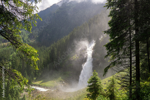 huge waterfall in the mountains between trees © Simon