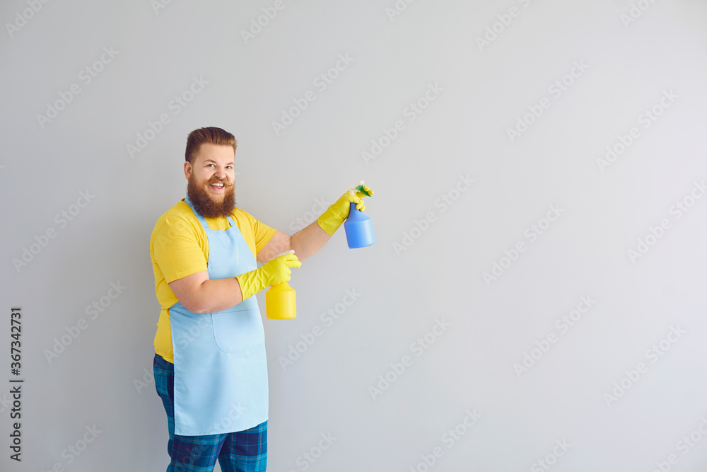 Cleaning service and housework concept. Happy funny guy with detergents on grey background, space for text Cleaning service and housework concept. Happy funny guy with detergents on grey background, space for text