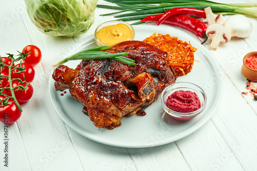 Photography Appetizing baked pork shank in beer and honey with fried cabbage and mustard