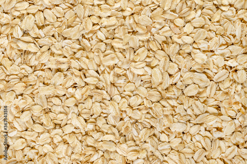 Rolled oats, close-up. Lightly processed whole-grain food. Husked and steamed oat groats rolled into flakes and lightly toasted to stabilize. Food photo, top view, from above, surface and background. Rolled oats, close-up. Lightly processed whole-grain food. Husked and steamed oat groats rolled into flakes and lightly toasted to stabilize. Food photo, top view, from above, surface and background.