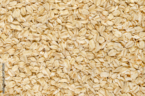 Rolled oats, close-up. Lightly processed whole-grain food. Husked and steamed oat groats rolled into flakes and lightly toasted to stabilize. Food photo, top view, from above, surface and background.