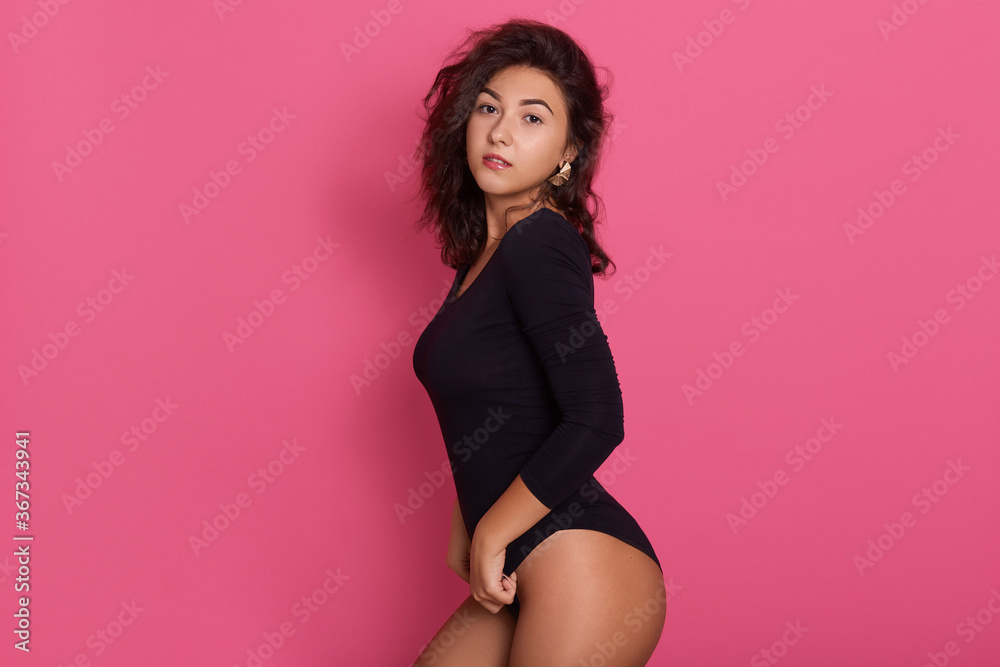 Photo of young beautiful woman dresses black combi dress, posing isolated over pink background, girl looking at camera, female with confident expression. Photo of young beautiful woman dresses black combi dress, posing isolated over pink background, girl looking at camera, female with confident expression.