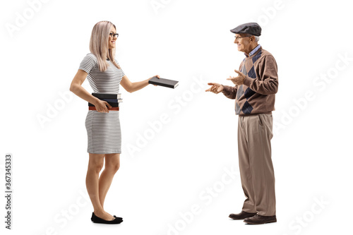 Full length profile shot of a young woman giving a book to an elderly gentleman