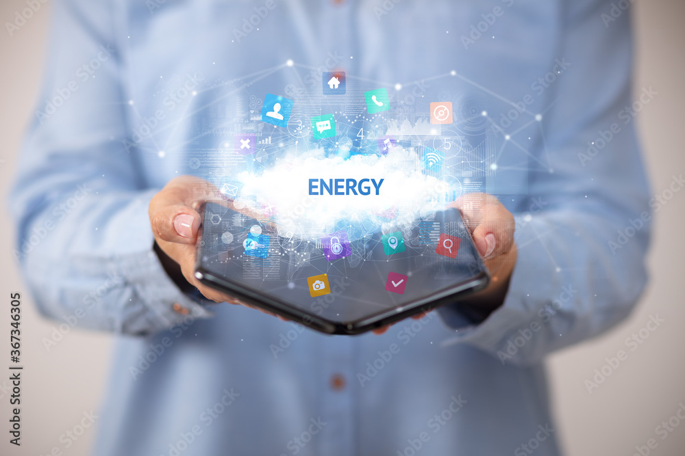 Businessman holding a foldable smartphone with ENERGY inscription, technology concept Businessman holding a foldable smartphone with ENERGY inscription, technology concept