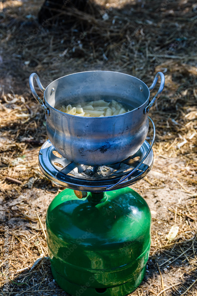 Pasta cooking in aluminium pan on a portable gas stove. Bushcraft or camping concept Pasta cooking in aluminium pan on a portable gas stove. Bushcraft or camping concept