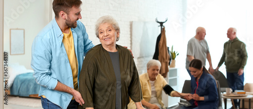 Young man taking care of elderly woman in geriatric hospice. Banner design