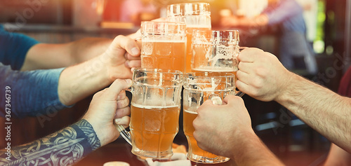 Group of friends toasting with beer in pub  closeup. Banner design