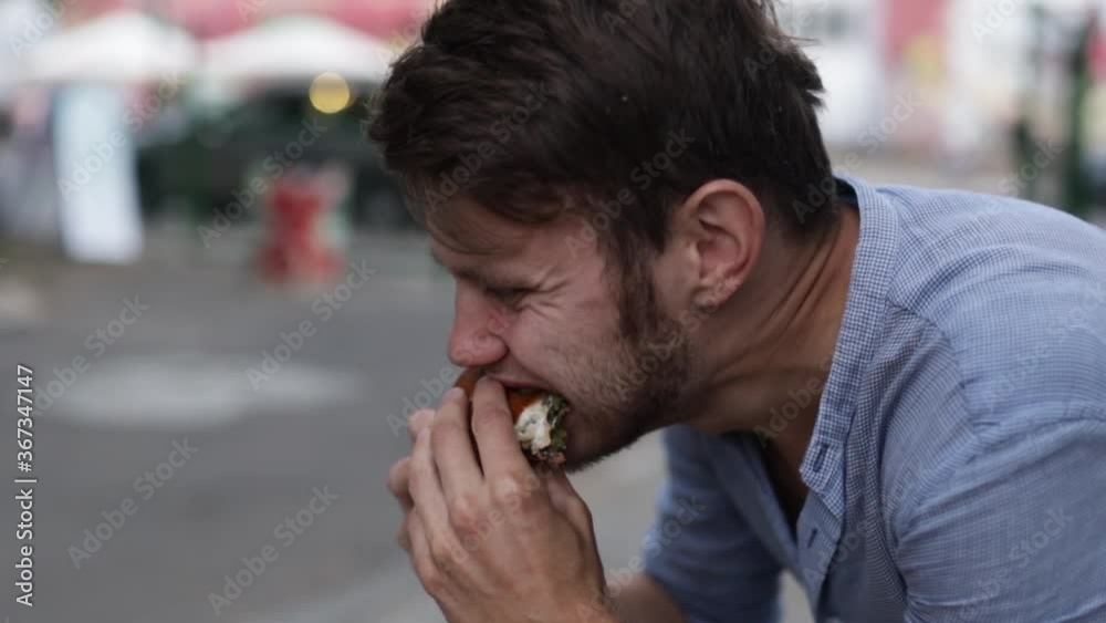 man greedily eating veggie burger with falafel in the city. man greedily eating veggie burger with falafel in the city.