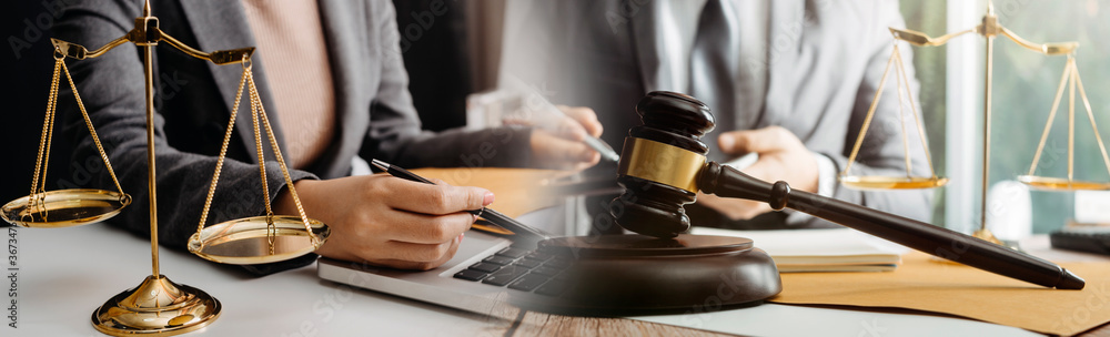 Justice and law concept.Male judge in a courtroom with the gavel, working with, computer and docking keyboard, eyeglasses, on table in morning light Justice and law concept.Male judge in a courtroom with the gavel, working with, computer and docking keyboard, eyeglasses, on table in morning light