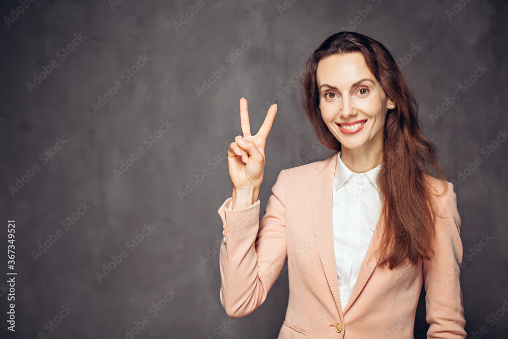 Adult woman show victory sign on dark background Adult woman show victory sign on dark background