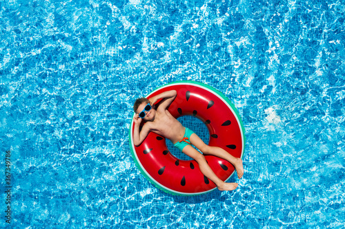 Cute little boy with inflatable ring in swimming pool  top view. Summer vacation