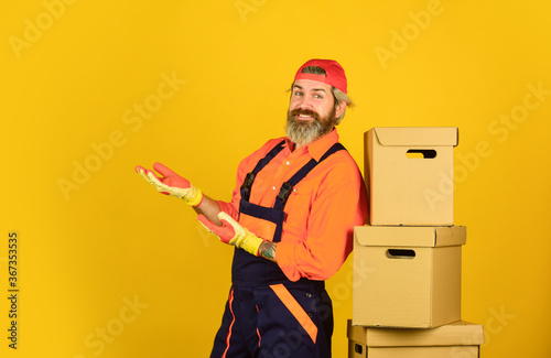 Successful engineer. move to new apartment. bearded loader in uniform. Cardboard boxes. moving to new house. purchase of new habitation or repair of room. Man wearing boilersuit packing boxes © be free