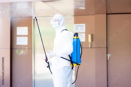 medical health care worker in protective white jumpsuit and pumping spraying machine disinfected virus pandemic in the office building