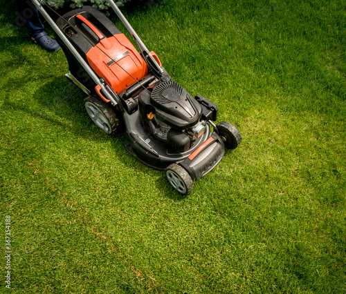Lawn mower on green grass. Summer garden