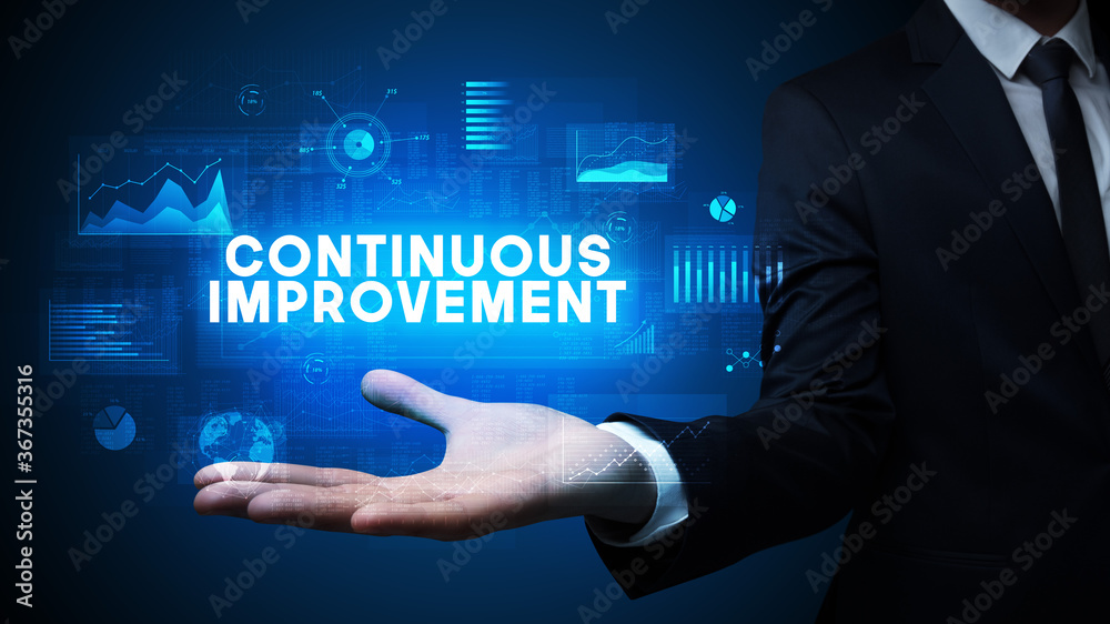 Hand of Businessman holding CONTINUOUS IMPROVEMENT inscription, business success concept Hand of Businessman holding CONTINUOUS IMPROVEMENT inscription, business success concept