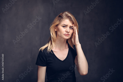 Tired young girl with headache on dark background
