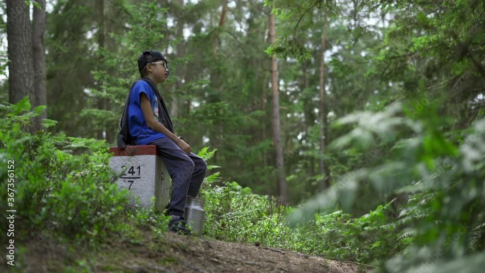Boy sitting on the concrete border post in the middle of the forest and and cries for help screaming echo Boy sitting on the concrete border post in the middle of the forest and and cries for help screaming echo