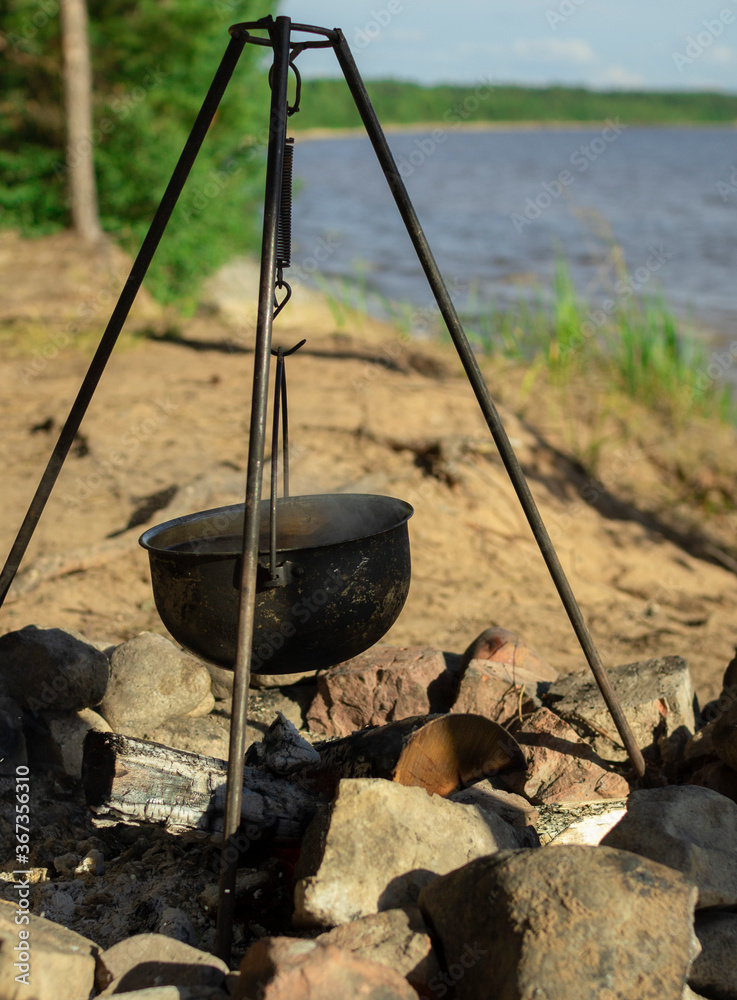 Pot on the fire by the lake. Camping with a pot over a burning fire. Pot on the fire by the lake. Camping with a pot over a burning fire.