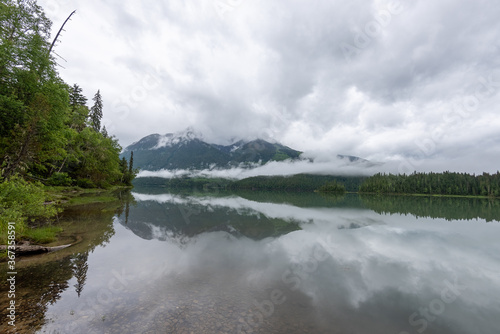 Low hanging clouds over the mountains and lake near Blue River British Columbia creating some great reflections in the water