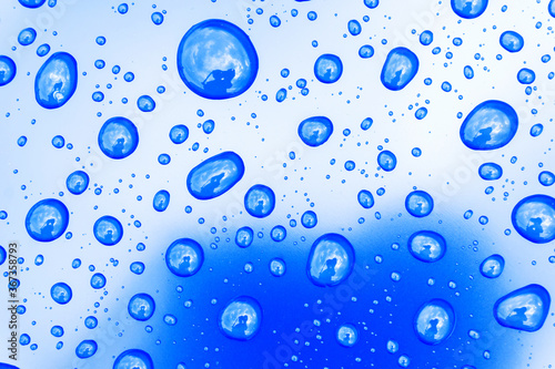 Large drops of rain on a blue background. Beautiful, natural background.