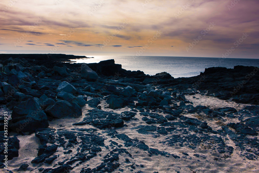 Fototapeta premium Sun setting over a rocky beach